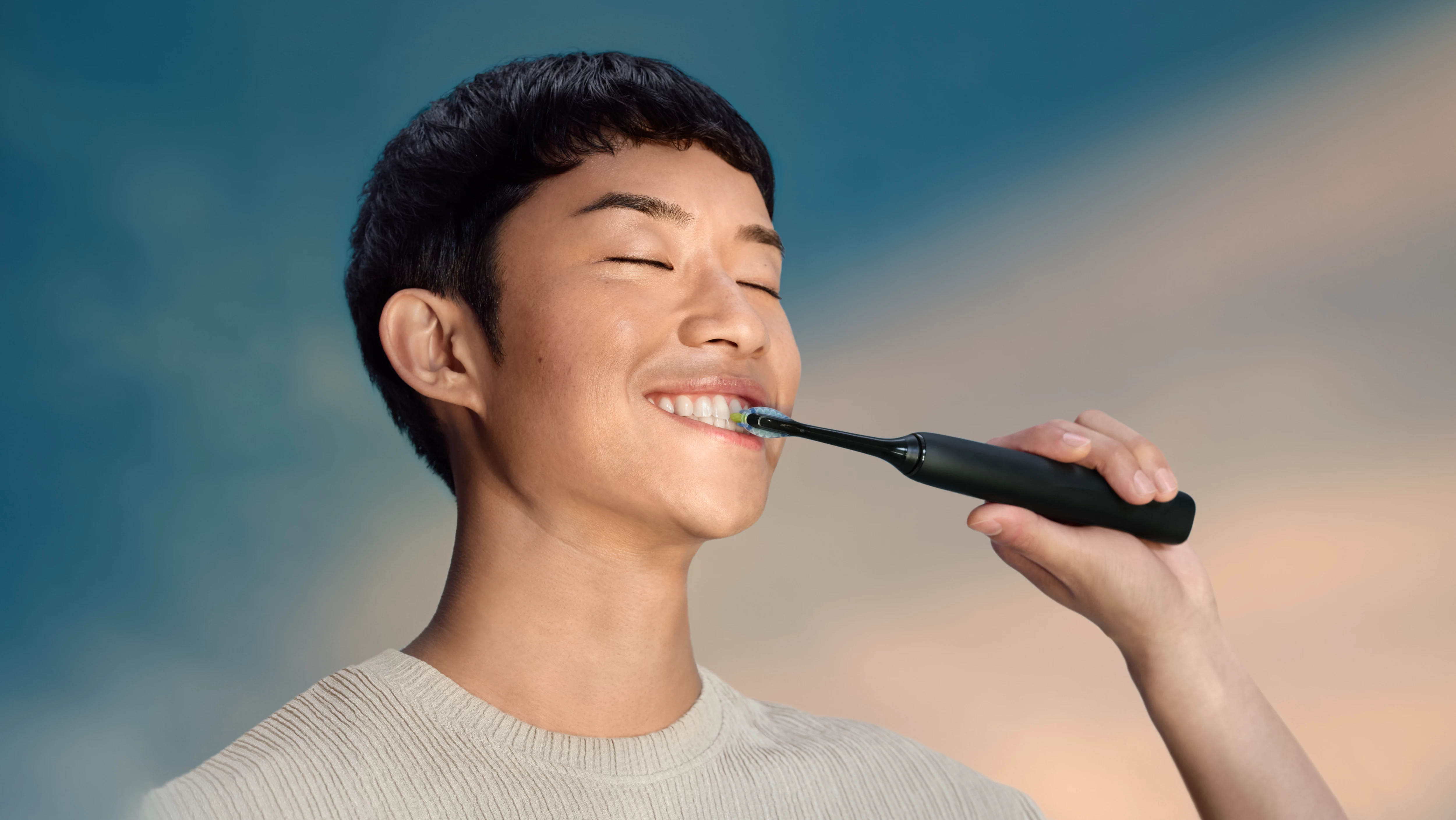 Mężczyzna myje zęby czarną szczoteczką elektryczną.