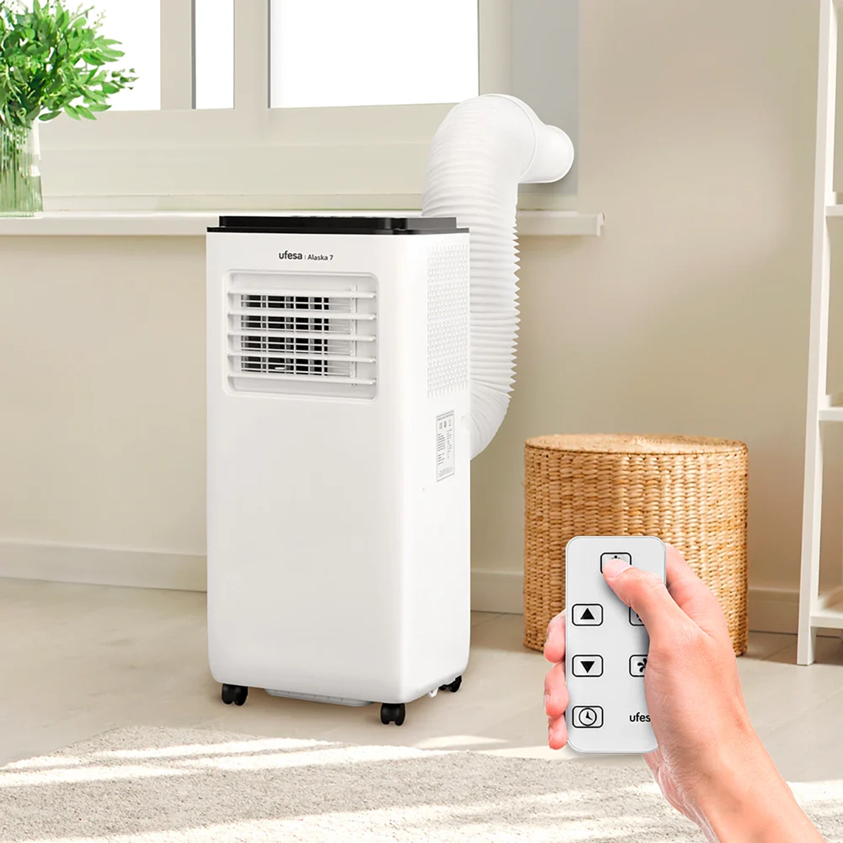 Biały przenośny klimatyzator z wężem, sterowany pilotem.