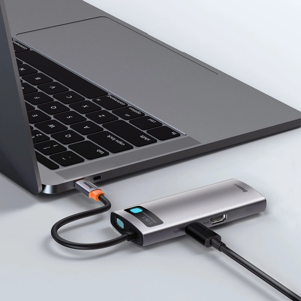 Srebrny hub USB-C Baseus 8 w 1 podłączony do laptopa, z wpiętym kablem ładującym.