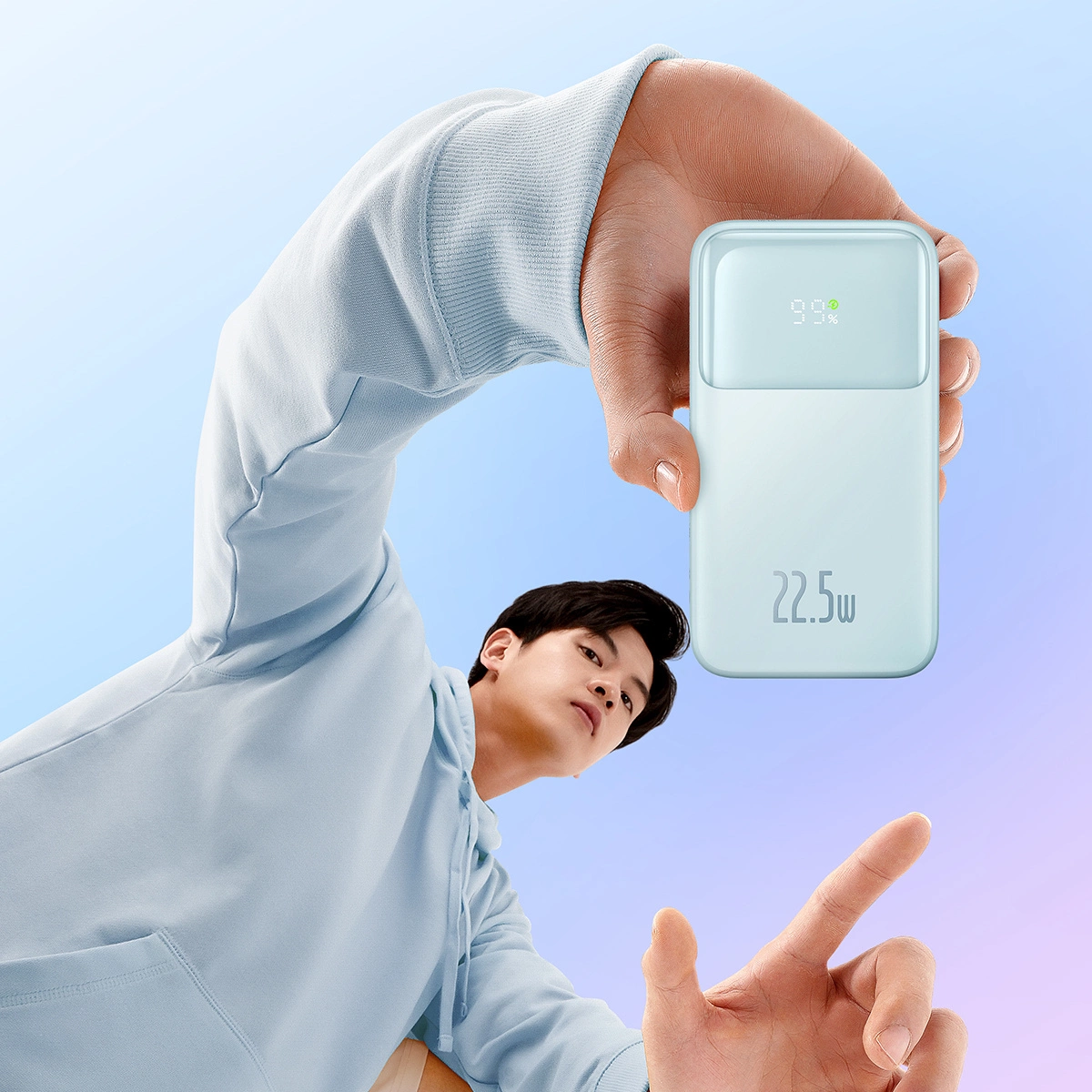 Osoba trzyma jasnoniebieski power bank z wyświetlaczem cyfrowym pokazującym 99% i 22,5W.