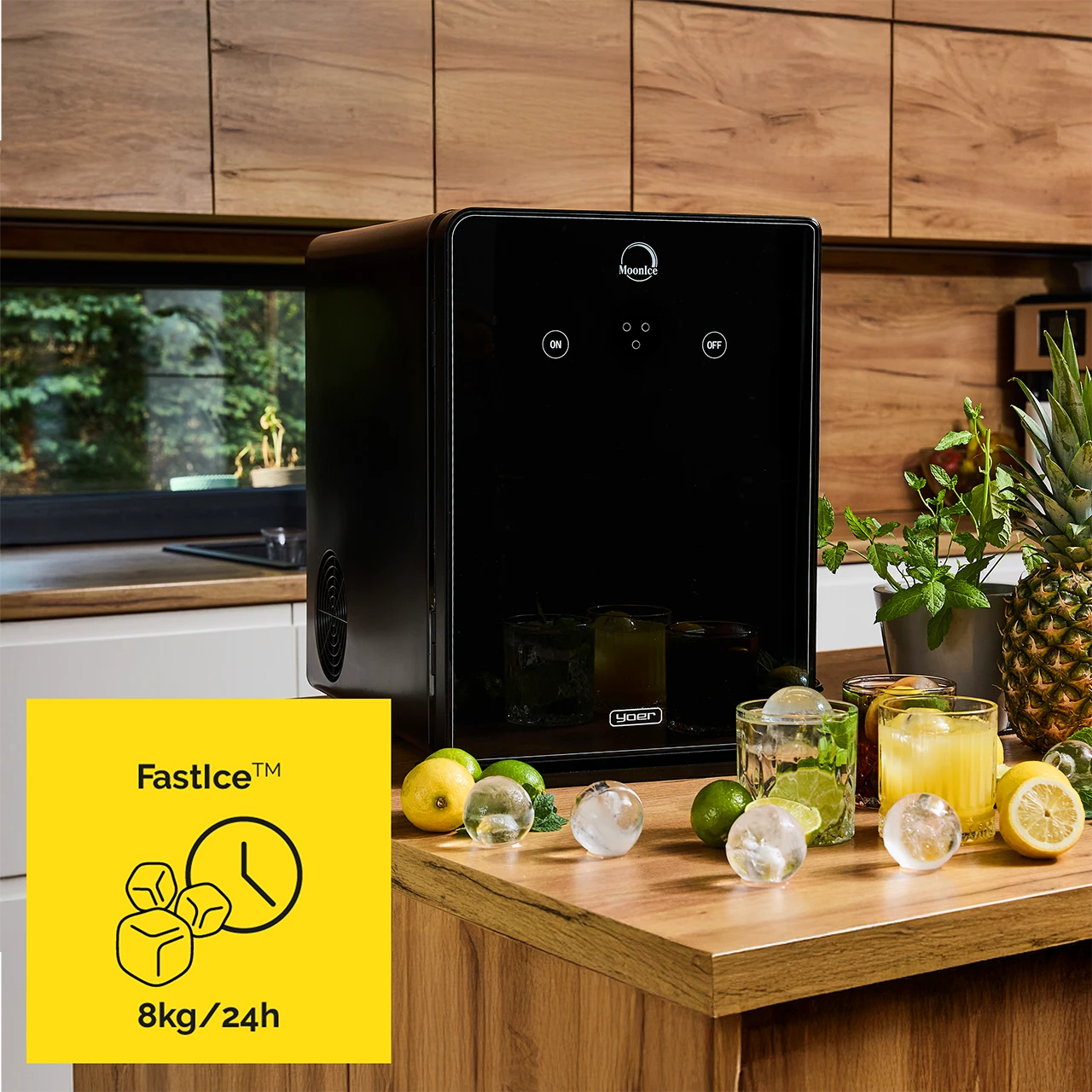 Czarna kostkarka do lodu ze szklankami, kulkami lodu, cytrynami, limonkami i ananasem na drewnianym blacie. Żółty znak mówi Fast Ice 8kg/24h.