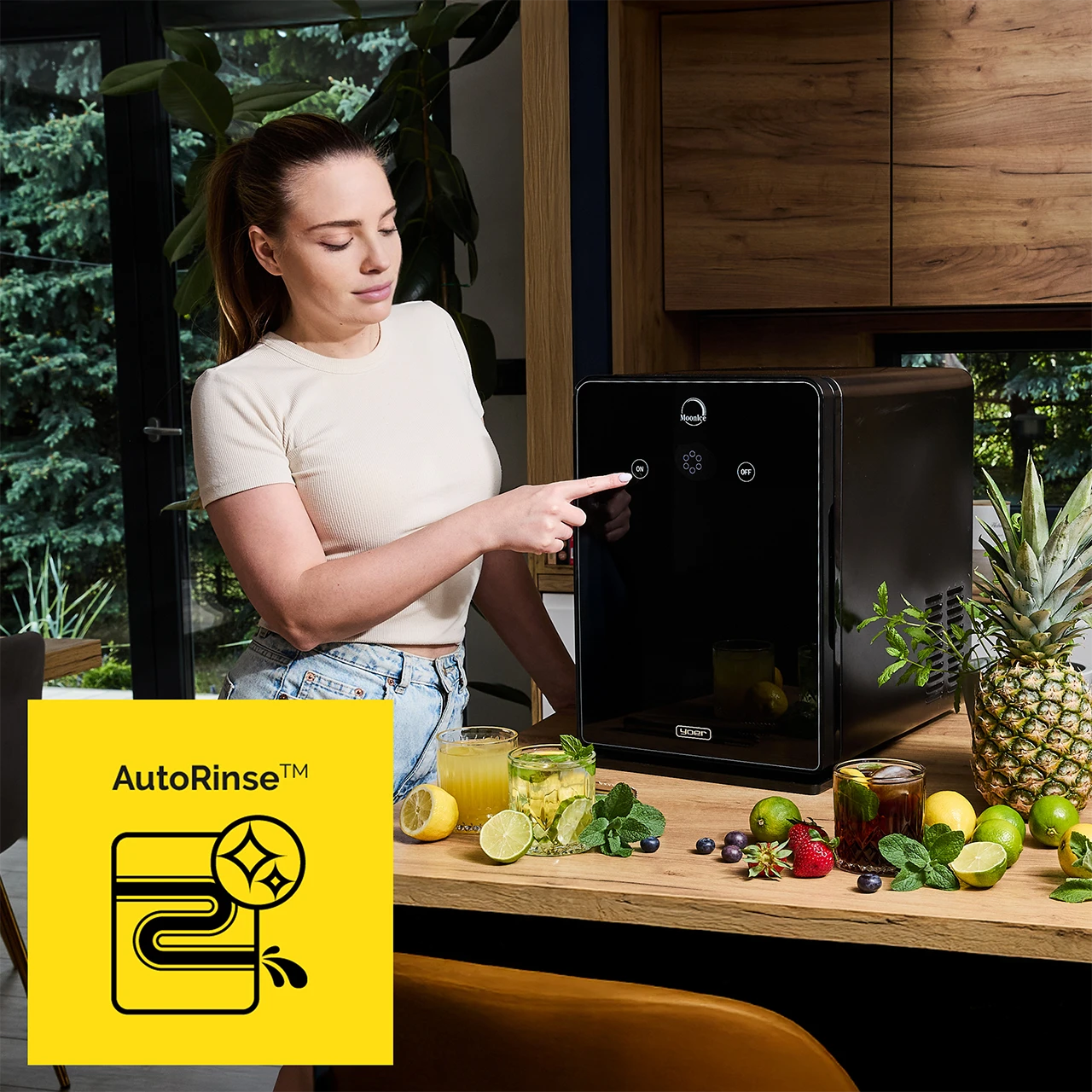 Kobieta wskazuje przycisk „włącz” na czarnym urządzeniu. Napoje i owoce na drewnianym blacie. Ananas i rośliny w tle.