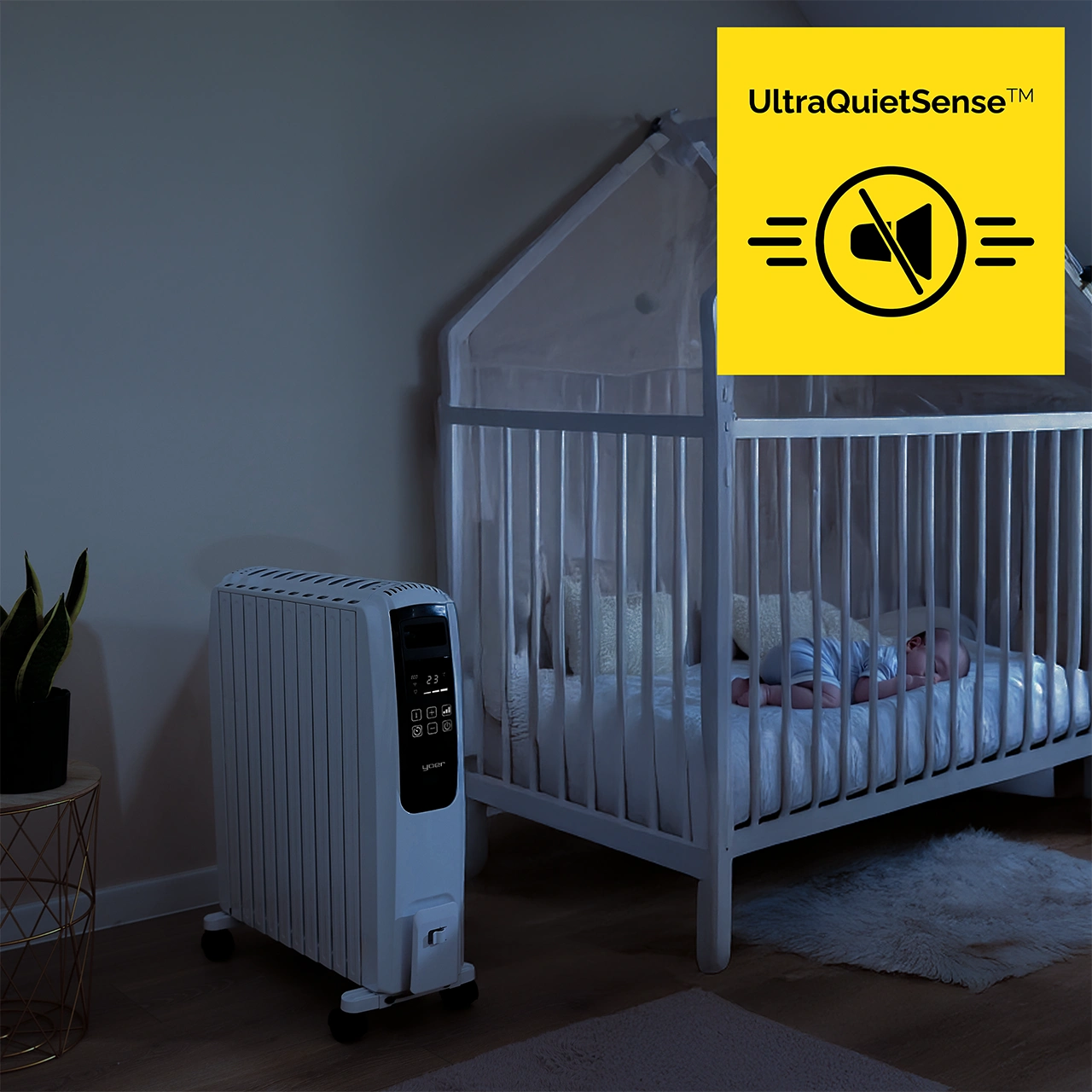 Dziecko śpi w kołysce. Biały grzejnik jest włączony. Logo mówi 'UltraQuietSense'. Pokój jest słabo oświetlony.