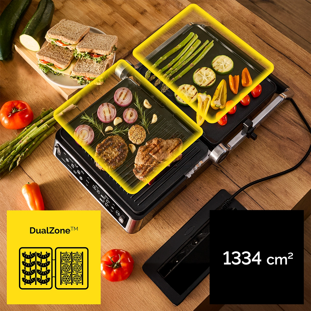 Grill z warzywami, mięsem, kanapkami, pomidorami i cukinią. Grill pokazuje symbol DualZone i 1334 cm2.