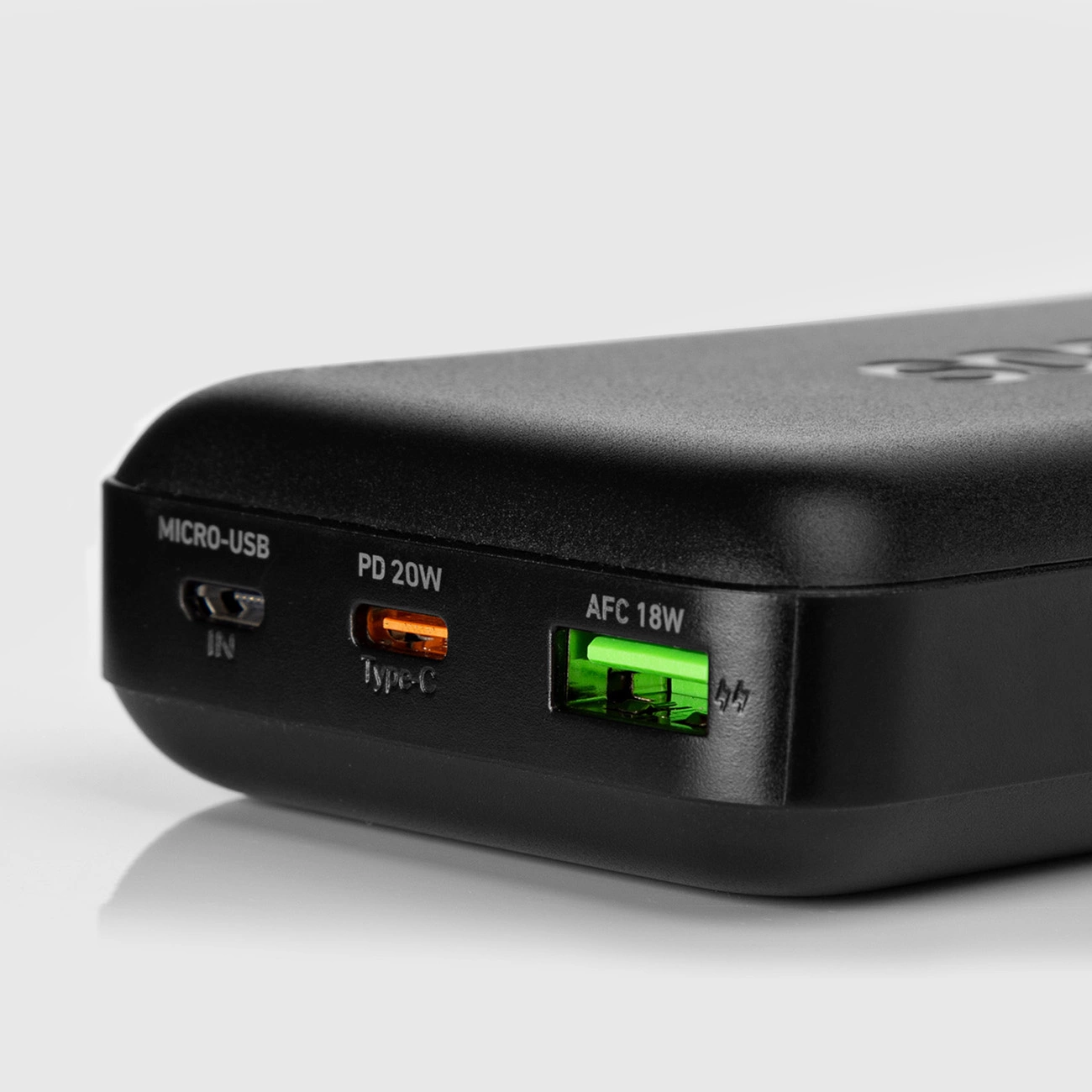 Zbliżenie czarnego power banku z portami Micro-USB, PD 20W Type-C i AFC 18W. Porty mają pomarańczowe i zielone akcenty.