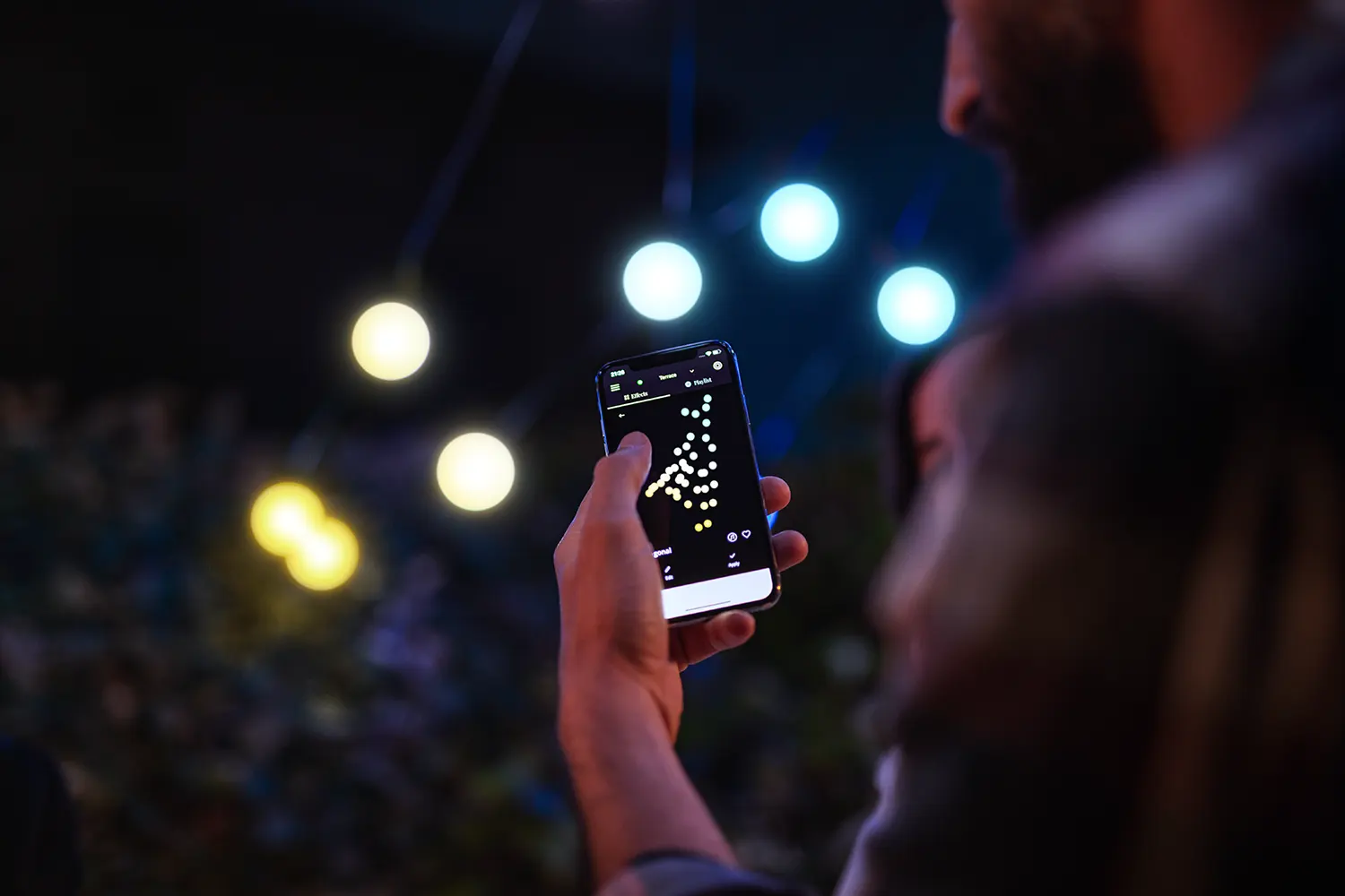 Mężczyzna trzyma smartfon z aplikacją świateł, światła w tle.