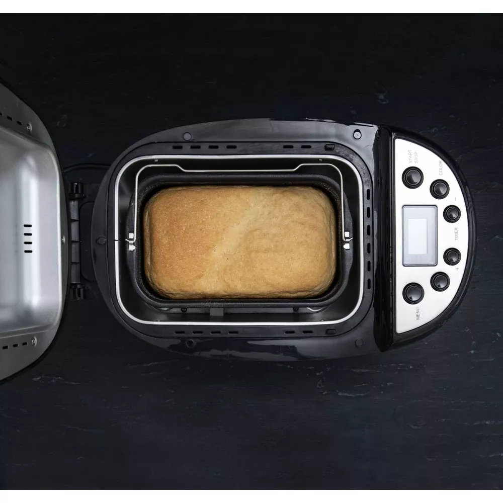 Złocistobrązowy bochenek chleba w otwartej maszynie do pieczenia chleba.