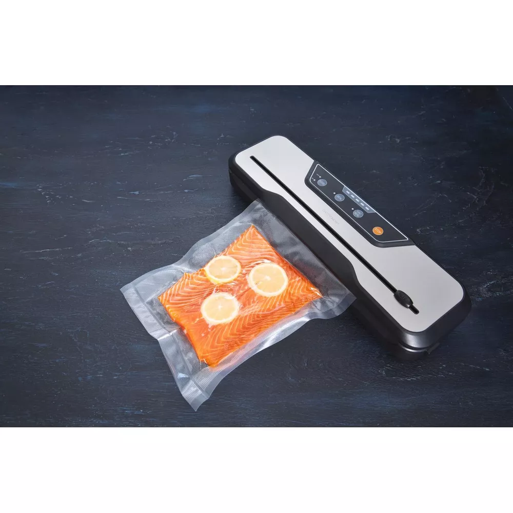 Filet łososia z plasterkami cytryny, zapakowany próżniowo obok srebrno-czarnej zgrzewarki.