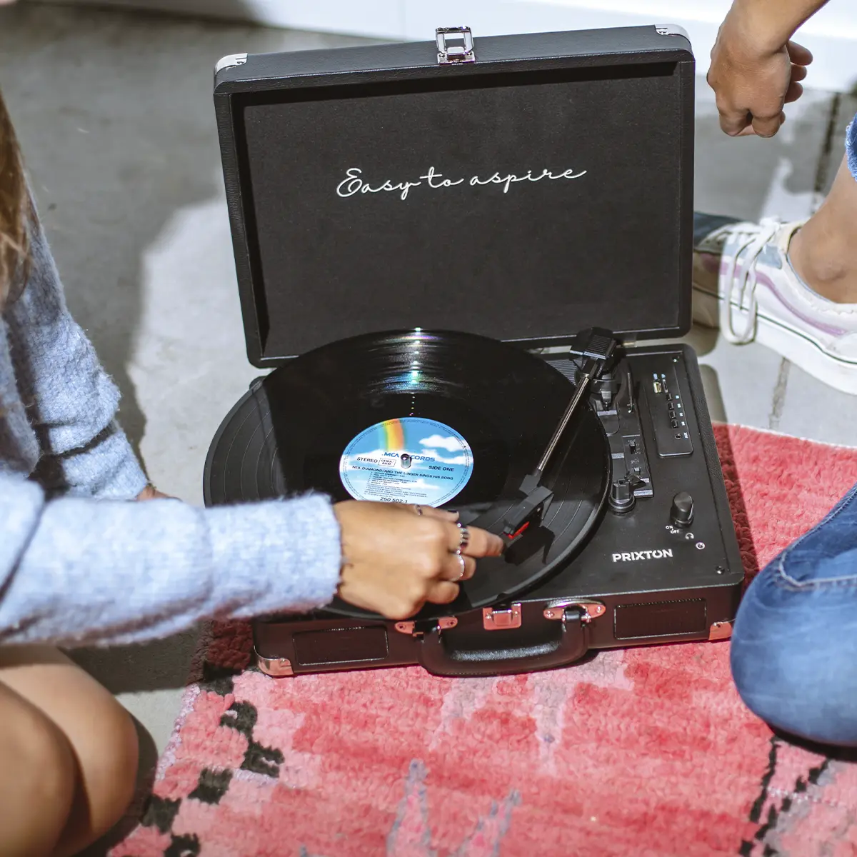 Ludzie słuchają płyty winylowej na gramofonie z napisem "Easy to aspire".