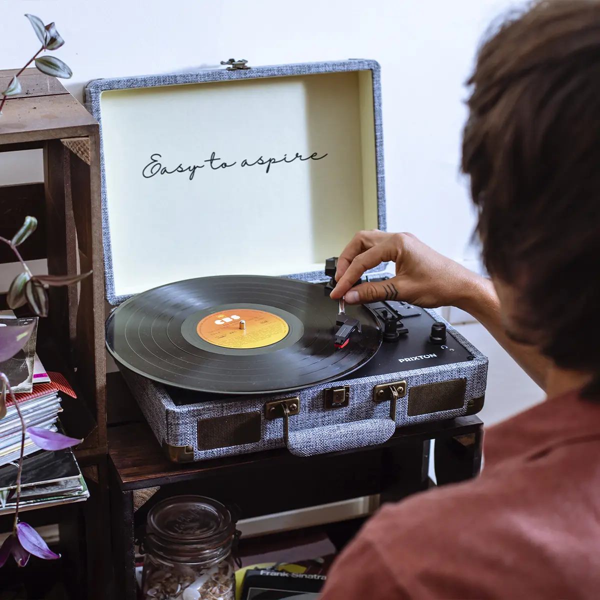 Osoba kładzie płytę na gramofonie. Wewnętrzna strona pokrywy głosi 'Easy to aspire'.