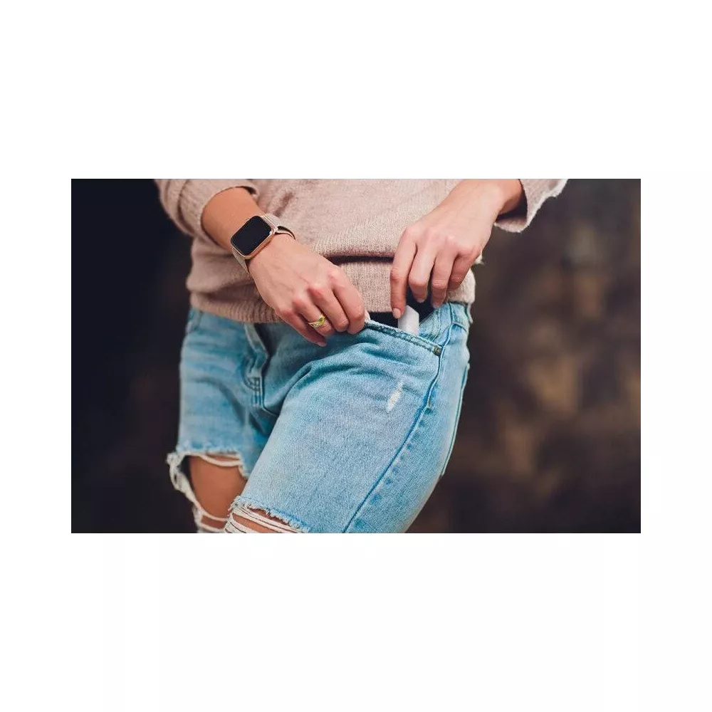 Kobieta wkłada długopis do kieszeni dżinsów.