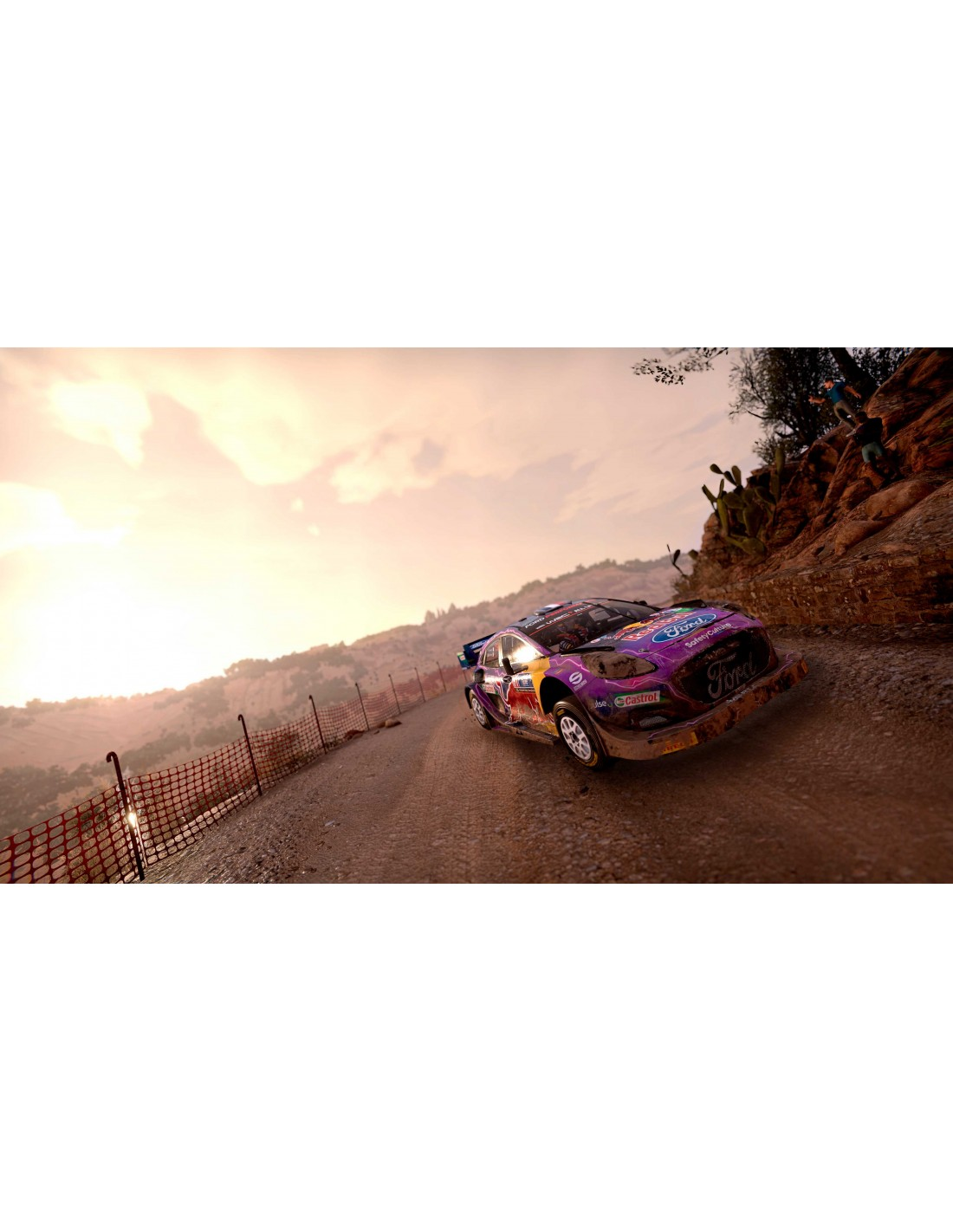 Un coche de rally en un camino de tierra en un paisaje montañoso, durante el atardecer.