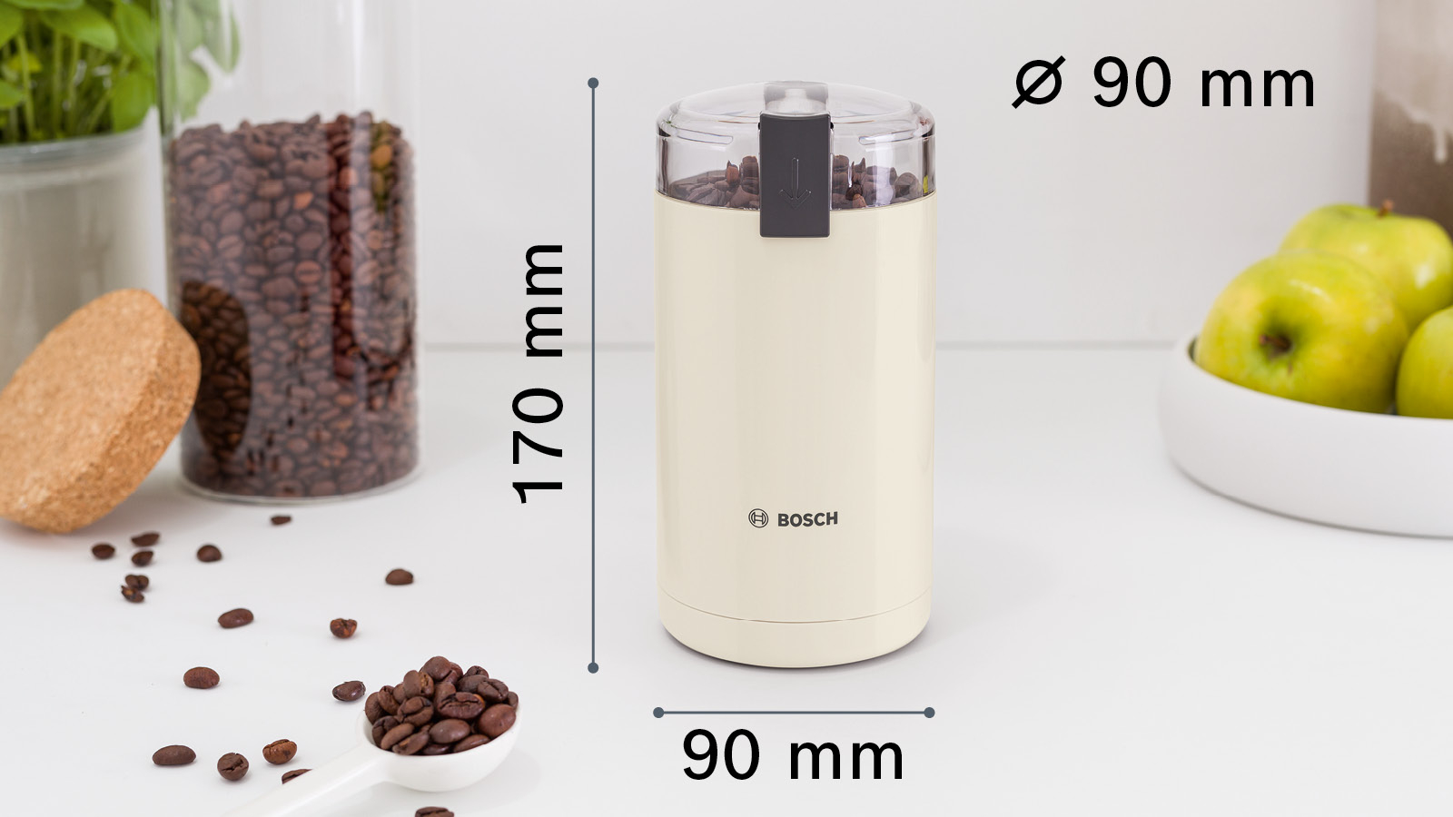 Eine cremefarbene Kaffeemühle mit Bohnen und einem Löffel Bohnen im Vordergrund.