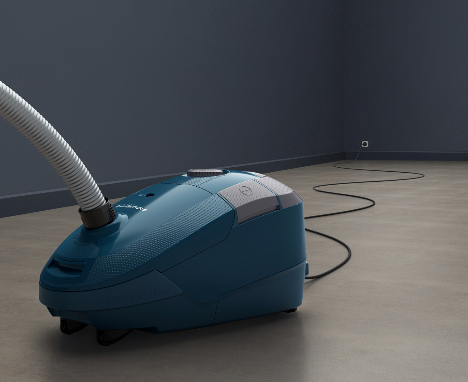 Teal vacuum cleaner on gray floor, hose connected, power cord extending to wall.