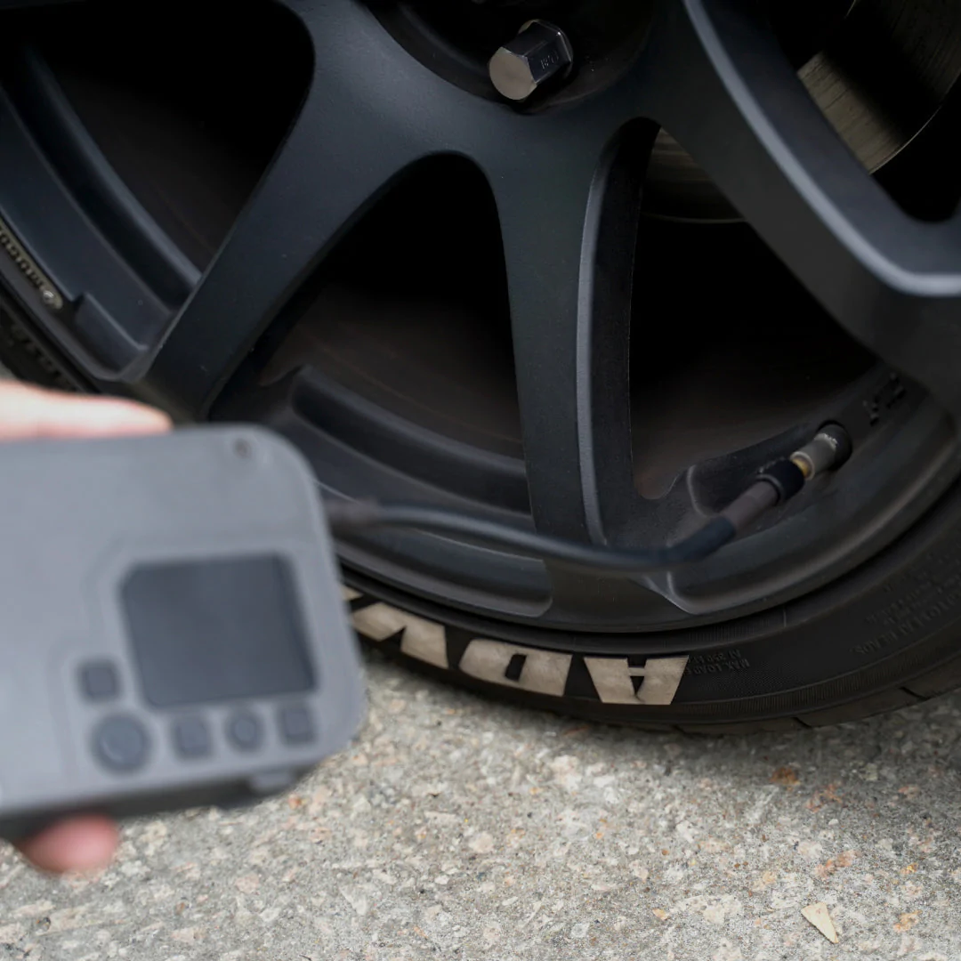 Une personne vérifiant la pression des pneus avec une jauge sur une roue de voiture.