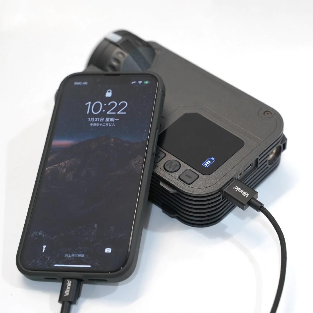 Un téléphone noir est connecté à un appareil noir avec un câble de chargement.