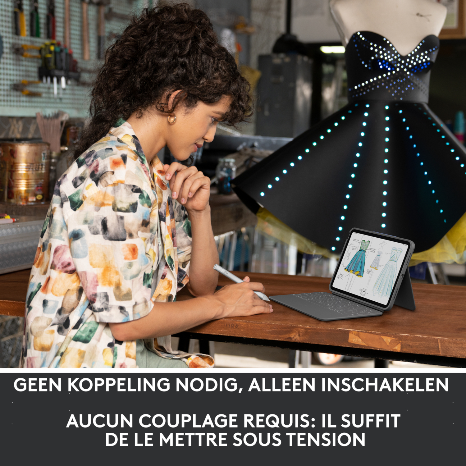 Woman drawing on a tablet, a dress form with a glowing dress in the background. Tools are visible.
