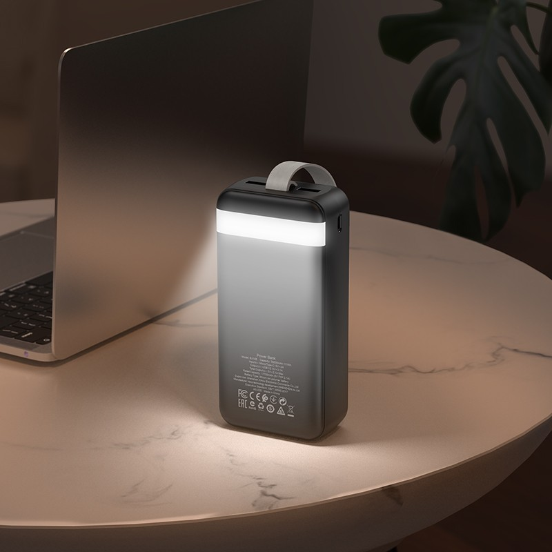 Fekete-szürke power bank fehér fénysávval az asztalon.