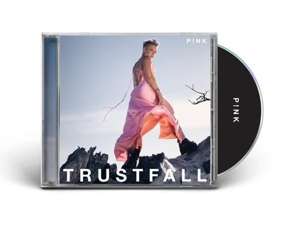 Rózsaszín CD-tok P!nkkel a borítón. Rózsaszín ruhát visel. A CD mellette van.
