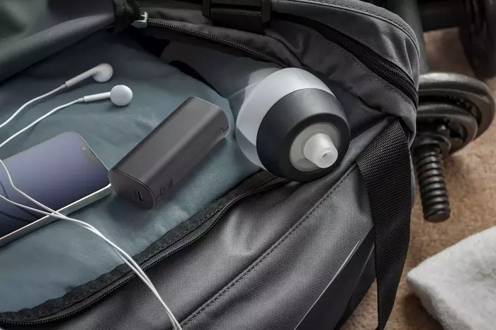 Eine Sporttasche ist offen und zeigt eine Wasserflasche, ein Telefon, Kopfhörer und ein Ladegerät.