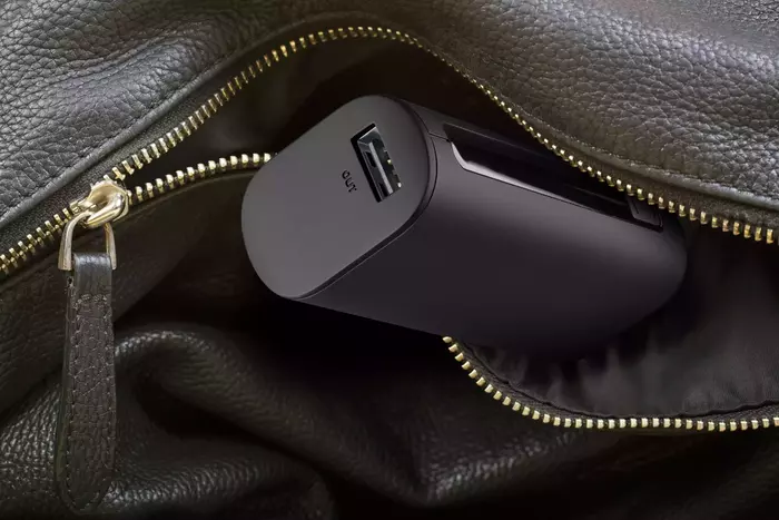 Eine schwarze Powerbank befindet sich teilweise in einer schwarzen Ledertasche mit Reißverschluss.
