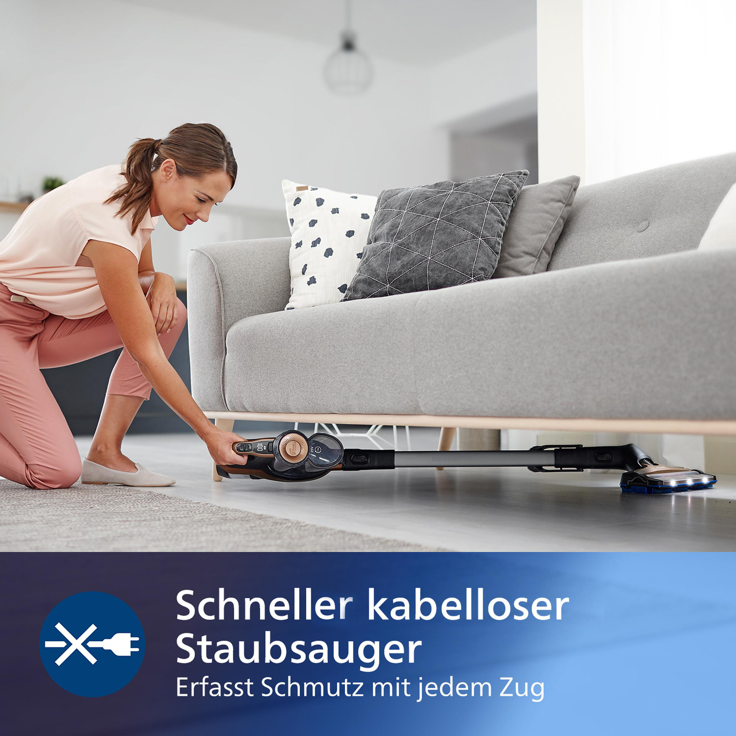 Eine Frau, die ein Wohnzimmer staubsaugt. Der Staubsauger befindet sich in der Nähe eines Sofas.