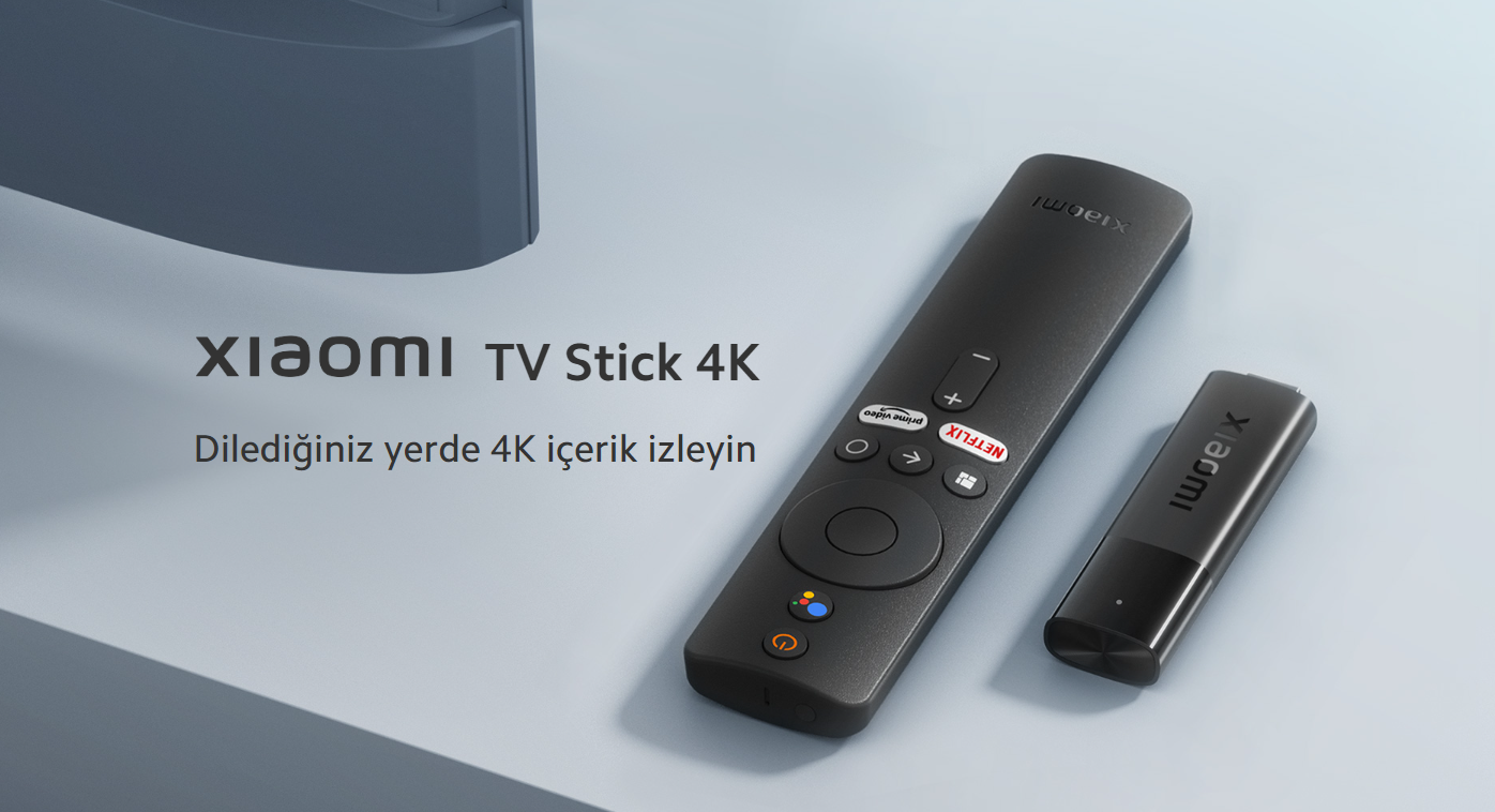 Gri bir yüzey üzerinde uzaktan kumanda ve bir dongle ile Xiaomi TV Stick 4K.