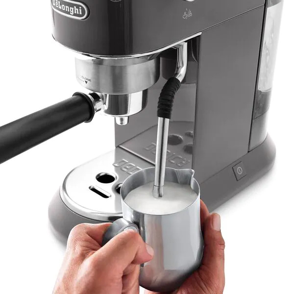 Une personne utilisant une machine à café, faisant mousser du lait.