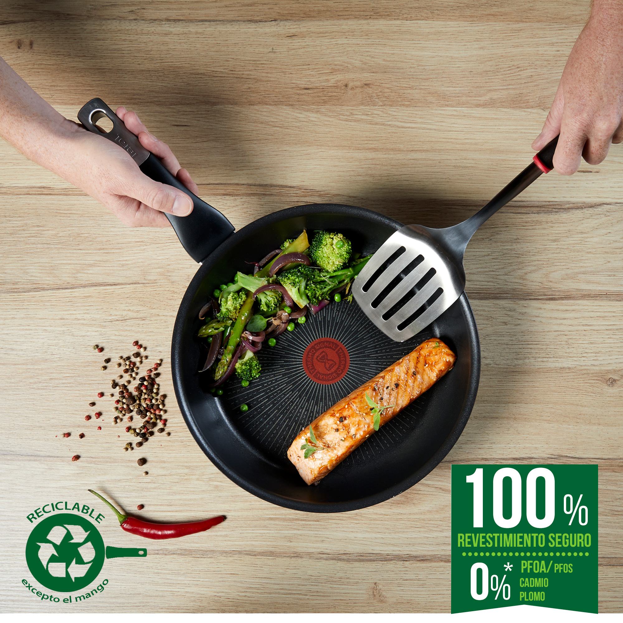 Una sartén con salmón cocido, verduras y especias que se sirve con dos manos.