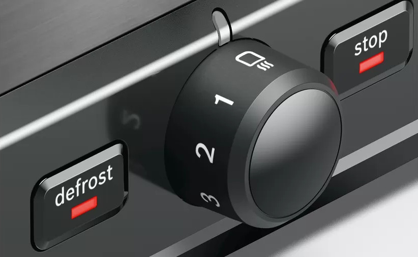 Close-up of a toaster's control panel with dial, and buttons for defrost and stop.