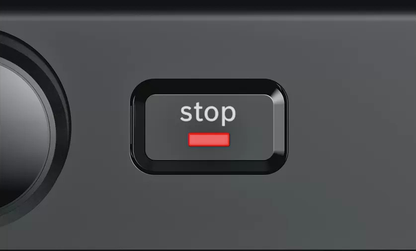 Close-up of a gray device with a red 'stop' button.