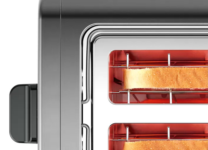 Close-up of a silver toaster with bread inside the slots, showing heating elements.