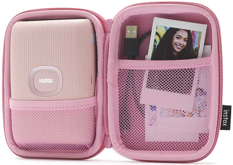Étui rose ouvert montrant l'appareil photo Instax, une photo et un câble USB.