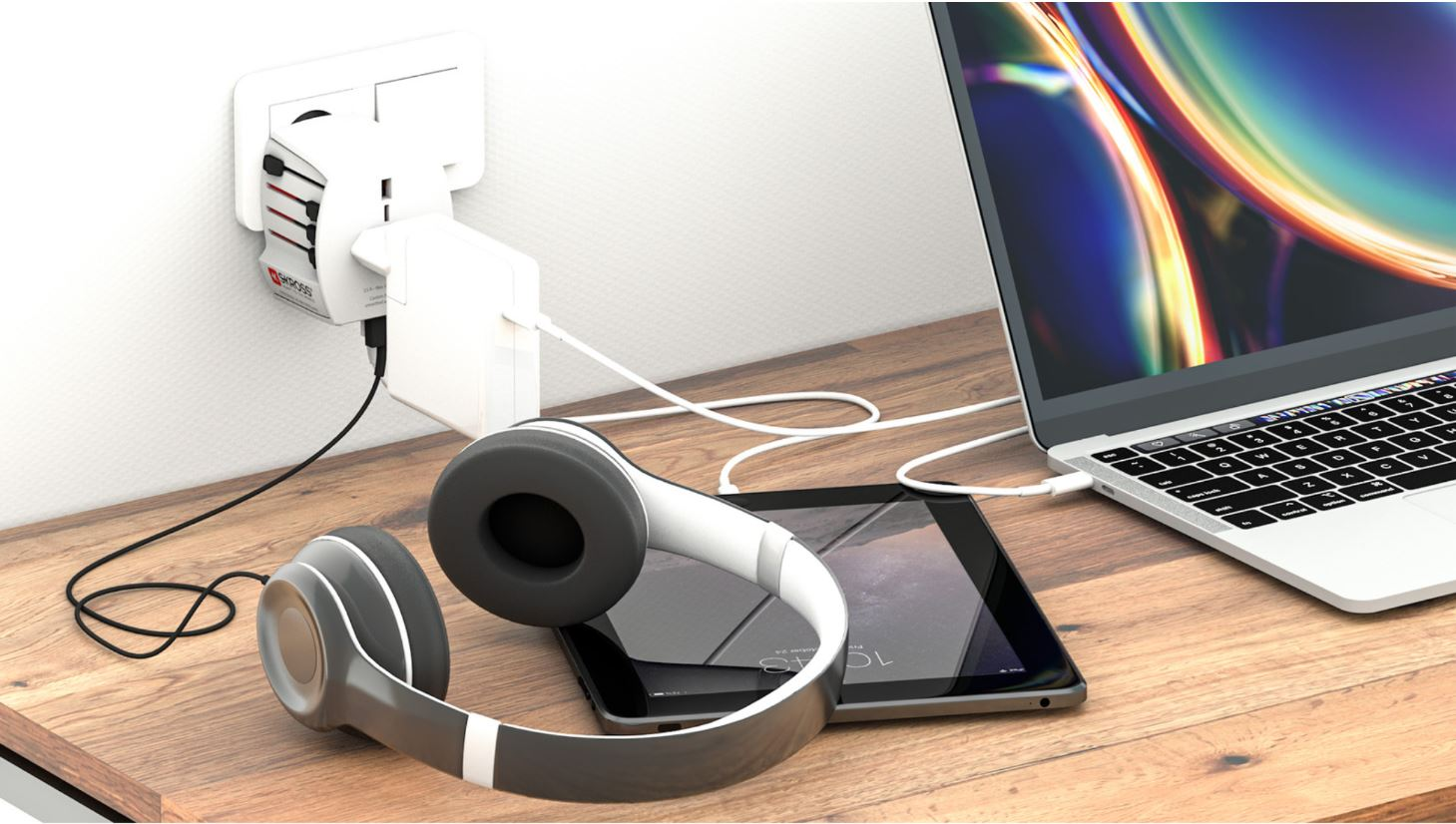 Casque, tablette, ordinateur portable et adaptateur branchés sur un bureau.