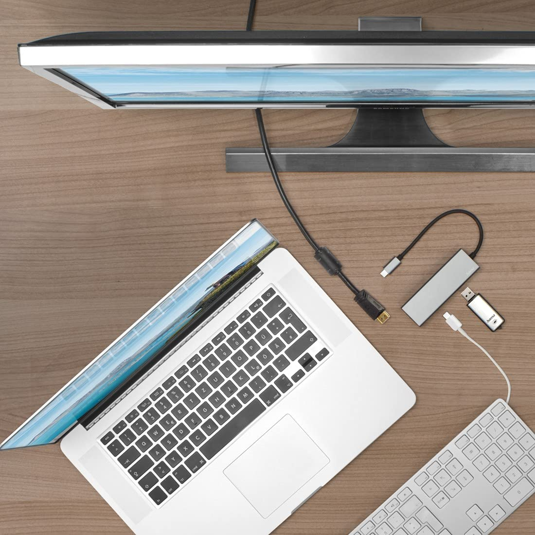 Laptop, monitor és egyéb eszközök egy fa asztalon.