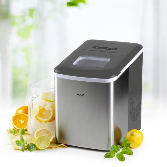 Stainless steel ice maker with pitcher of lemonade. Lemons and oranges around the machine.