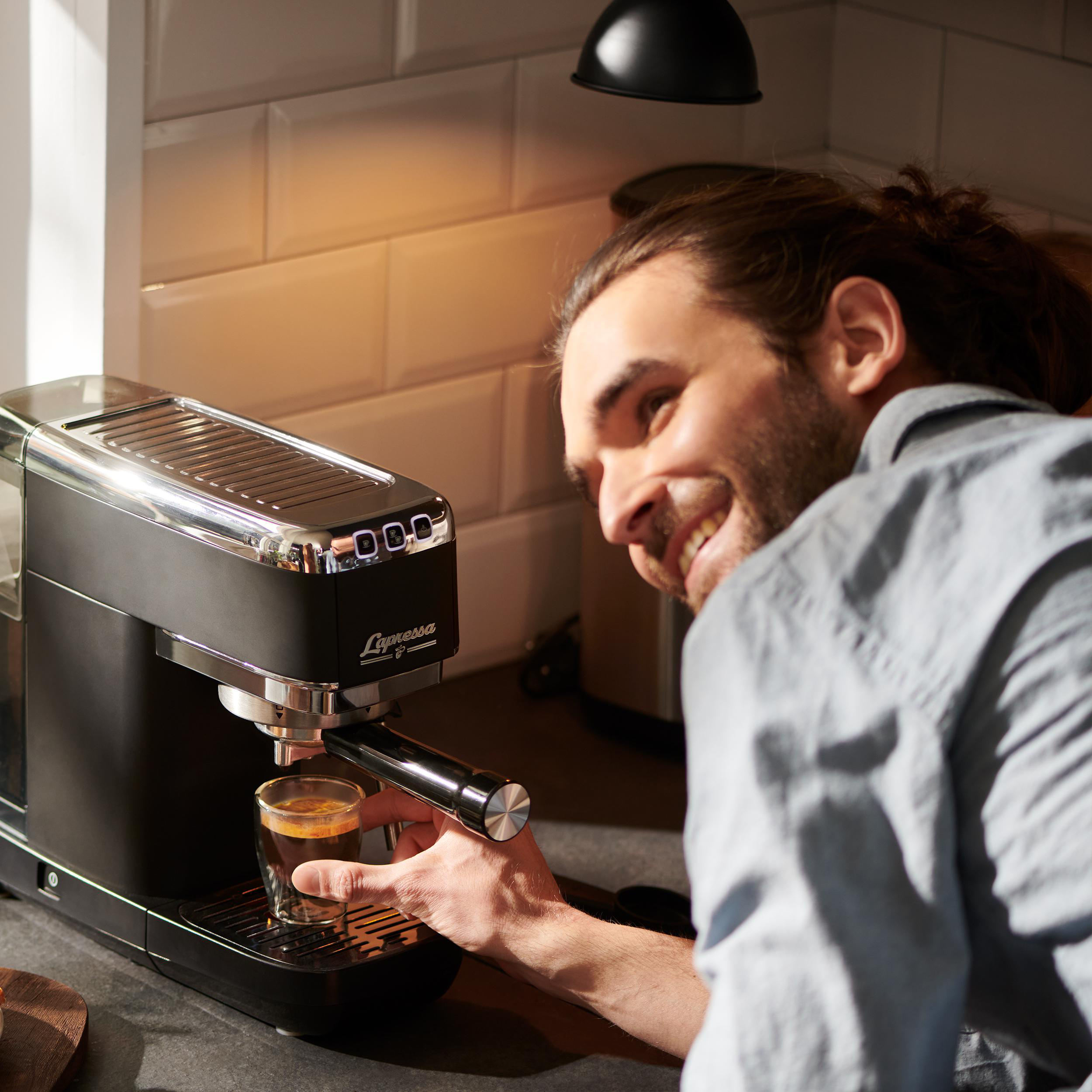 Mann lächelt, benutzt eine Espressomaschine.