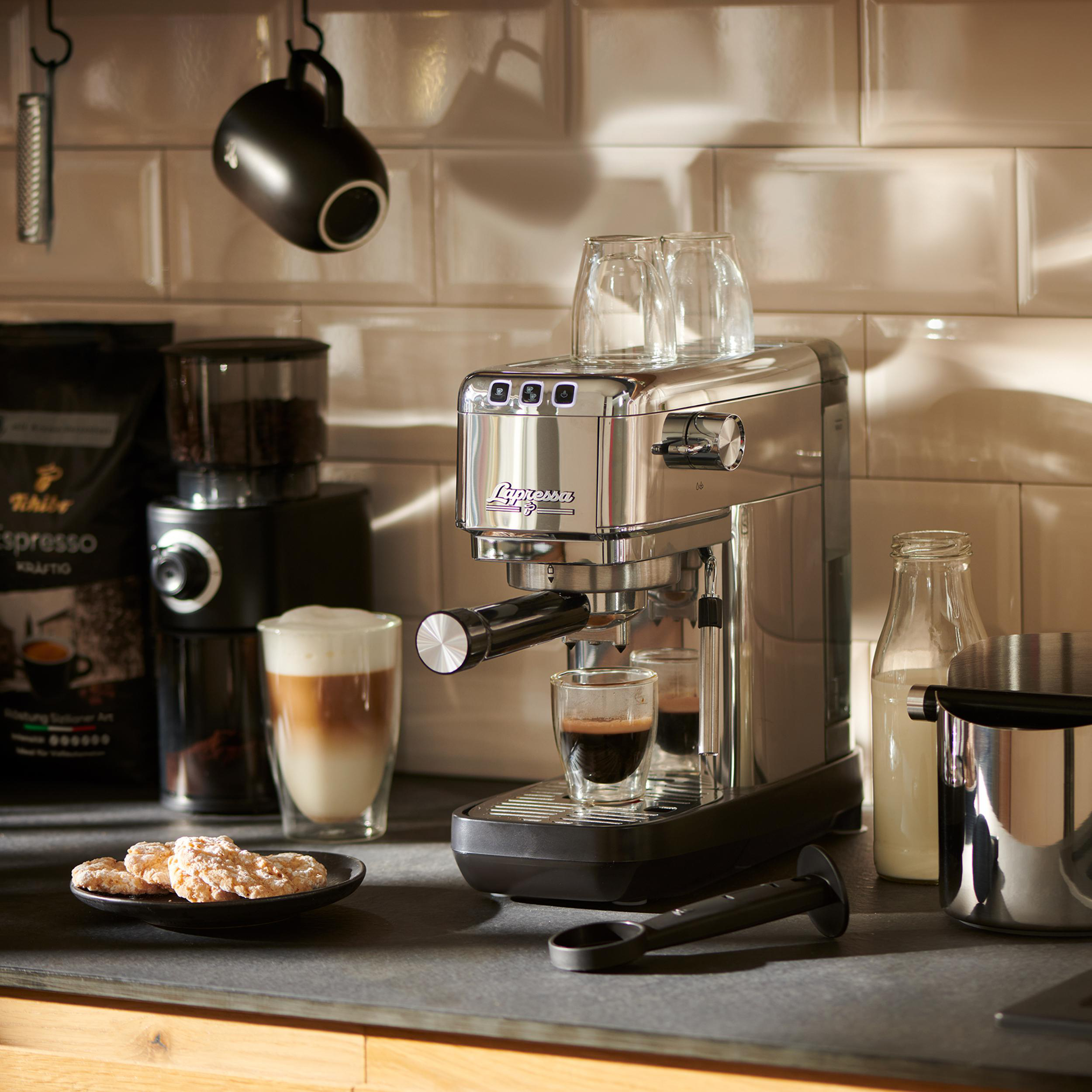 Eine Chrom-Espressomaschine mit zwei Shots, einer Kaffeemühle und einer schwarzen Tasse.