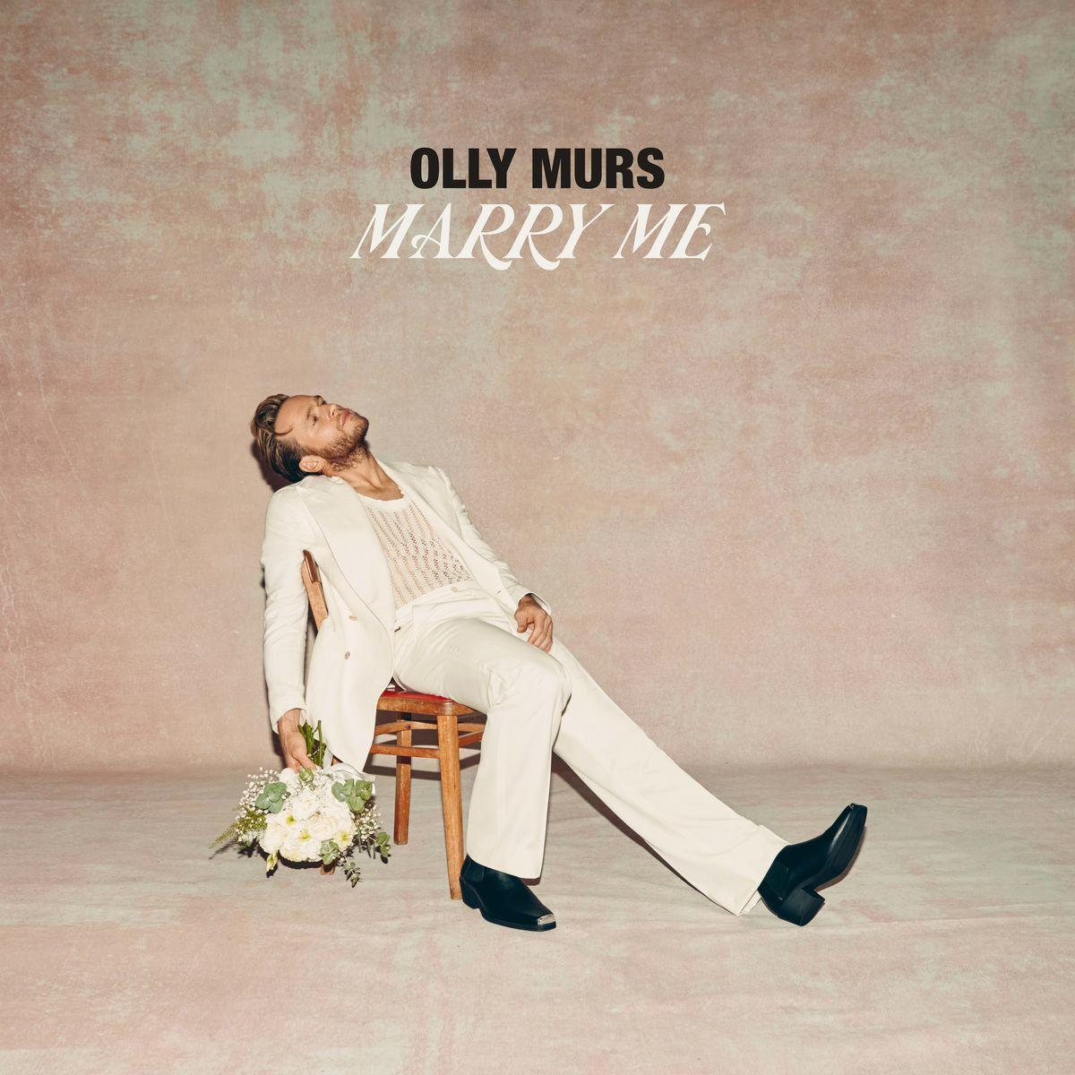 Albumcover von Olly Murs, auf Stuhl liegend, mit Blumen und weißem Anzug.