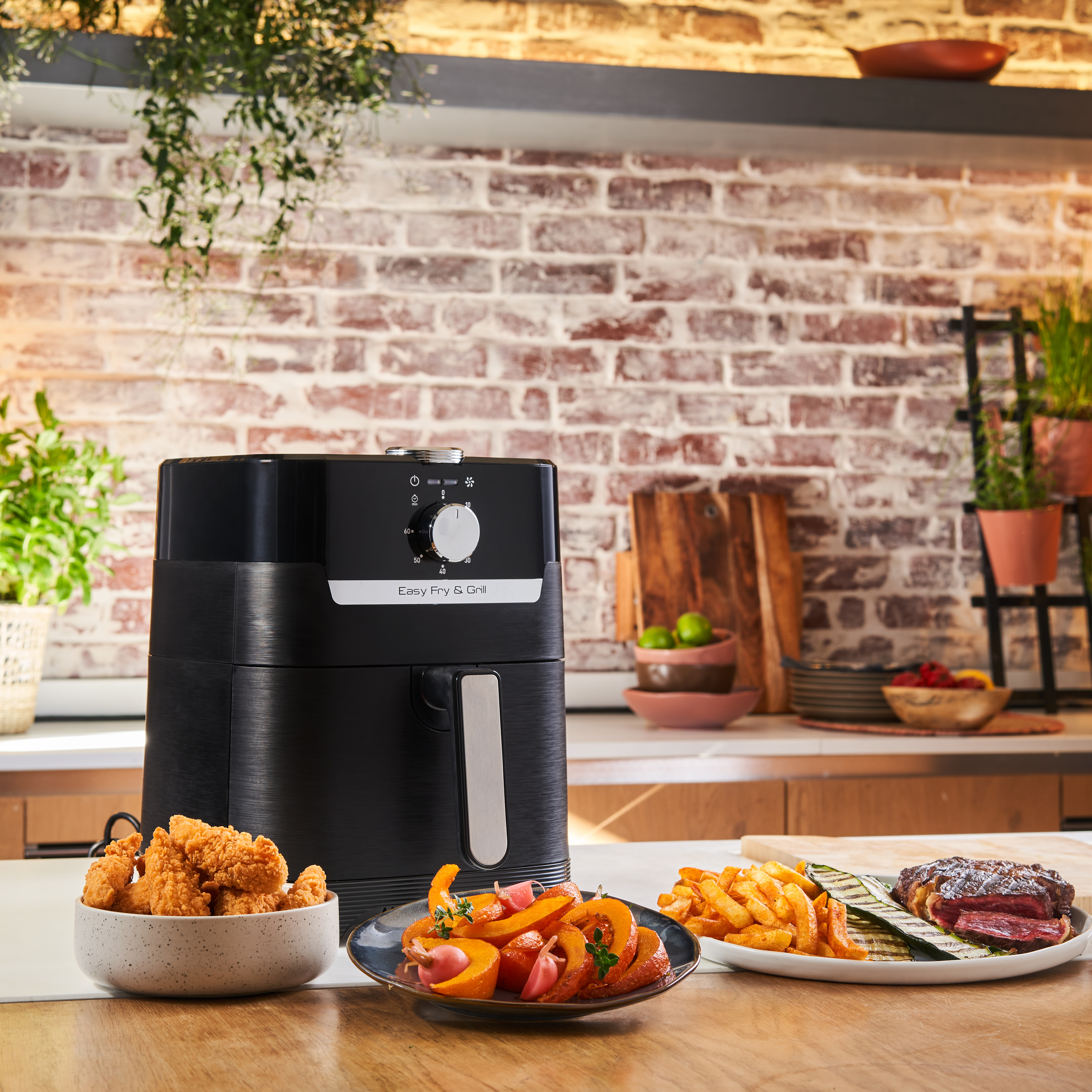 Friteuse à air noire avec aliments préparés. Poulet frit, frites et autres plats sur la table.