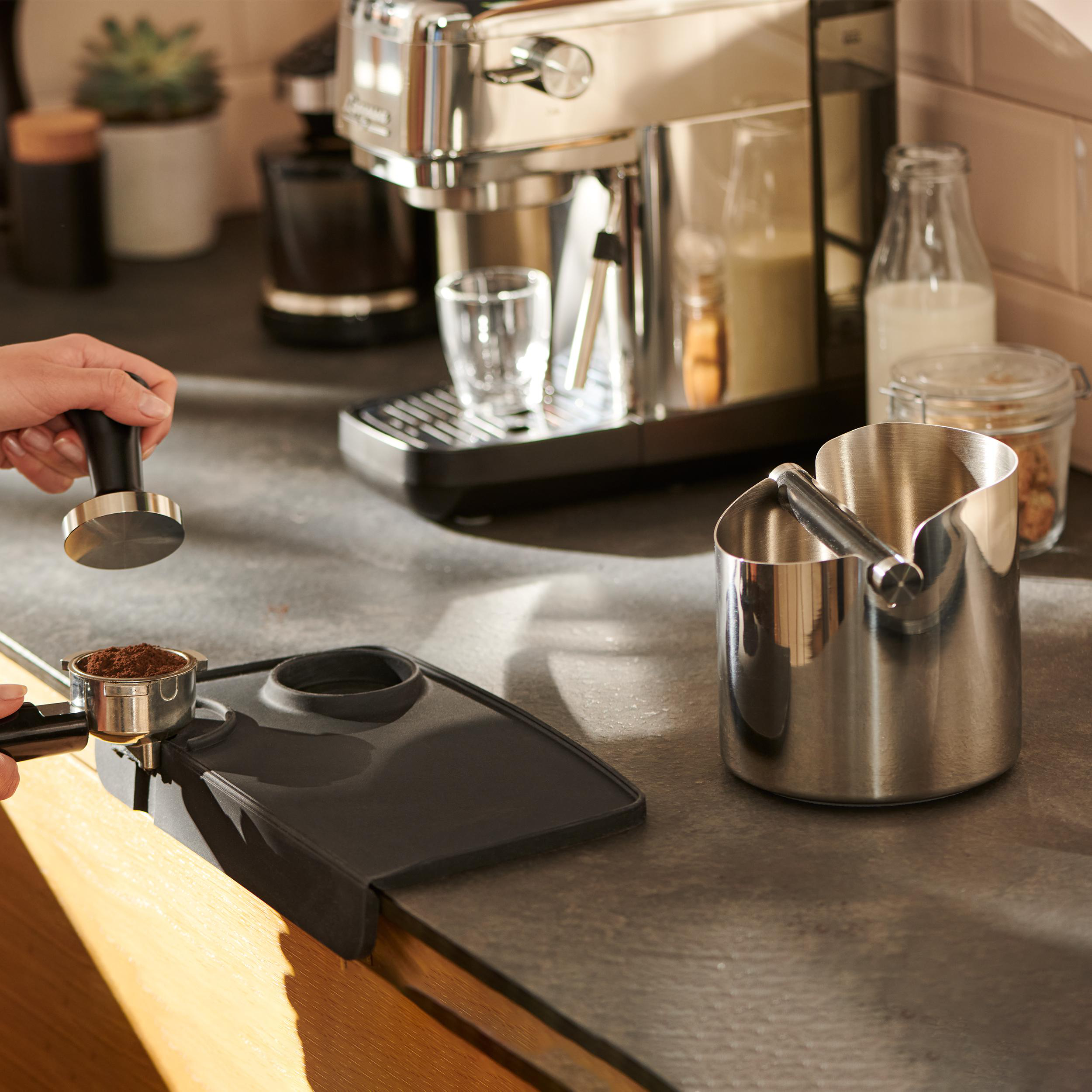 Person bereitet Kaffee mit Tamper, Siebträger und Espressomaschine zu.