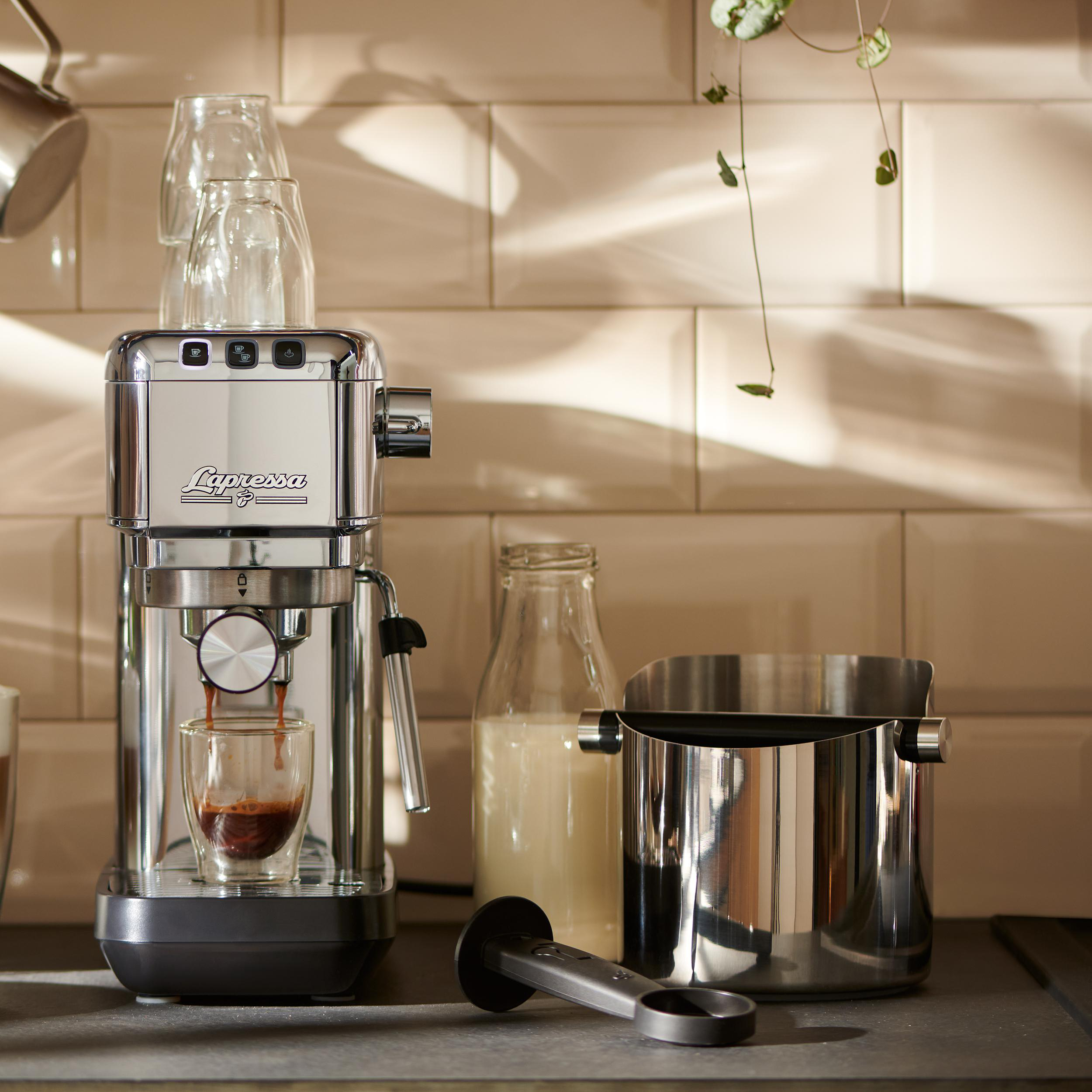 Eine Espressomaschine mit einem Glas Kaffee, einer Milchflasche und Kaffeezubehör.