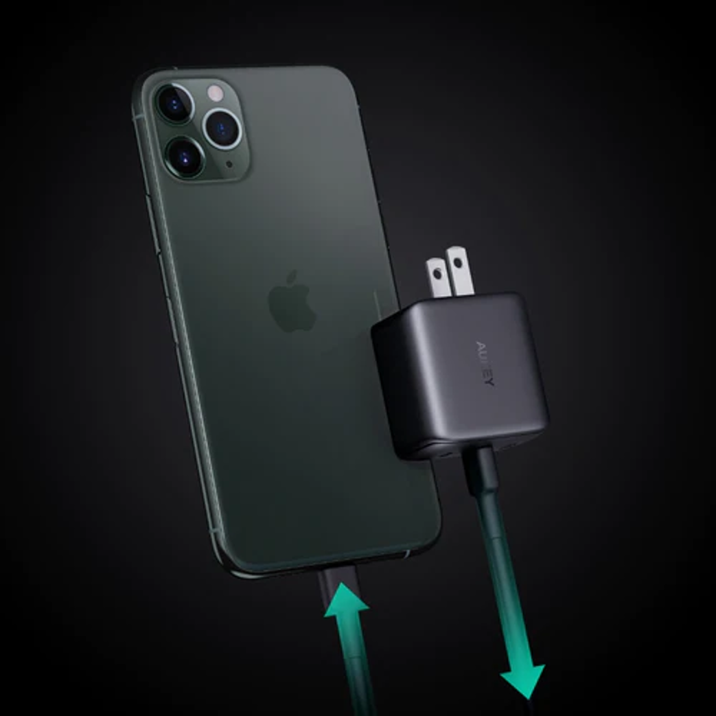 Un telefono nero è collegato a un caricabatterie nero. Frecce verdi indicano il flusso di energia.