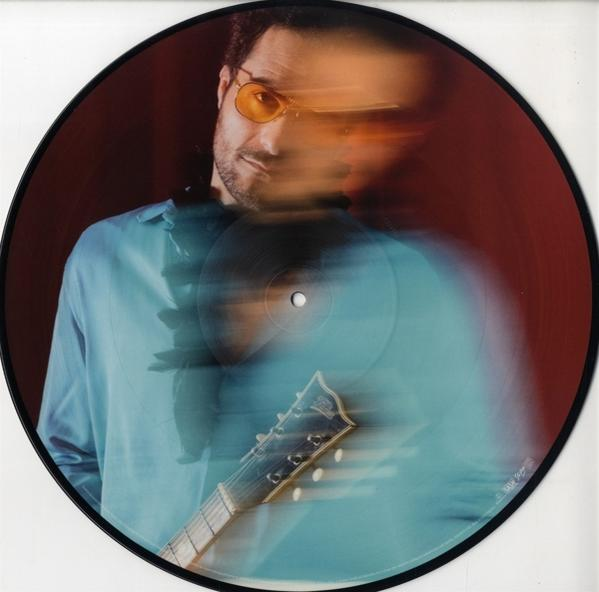 Verschwommenes Bild eines Mannes mit Sonnenbrille, der eine Gitarre hält, in einer Schallplatte.