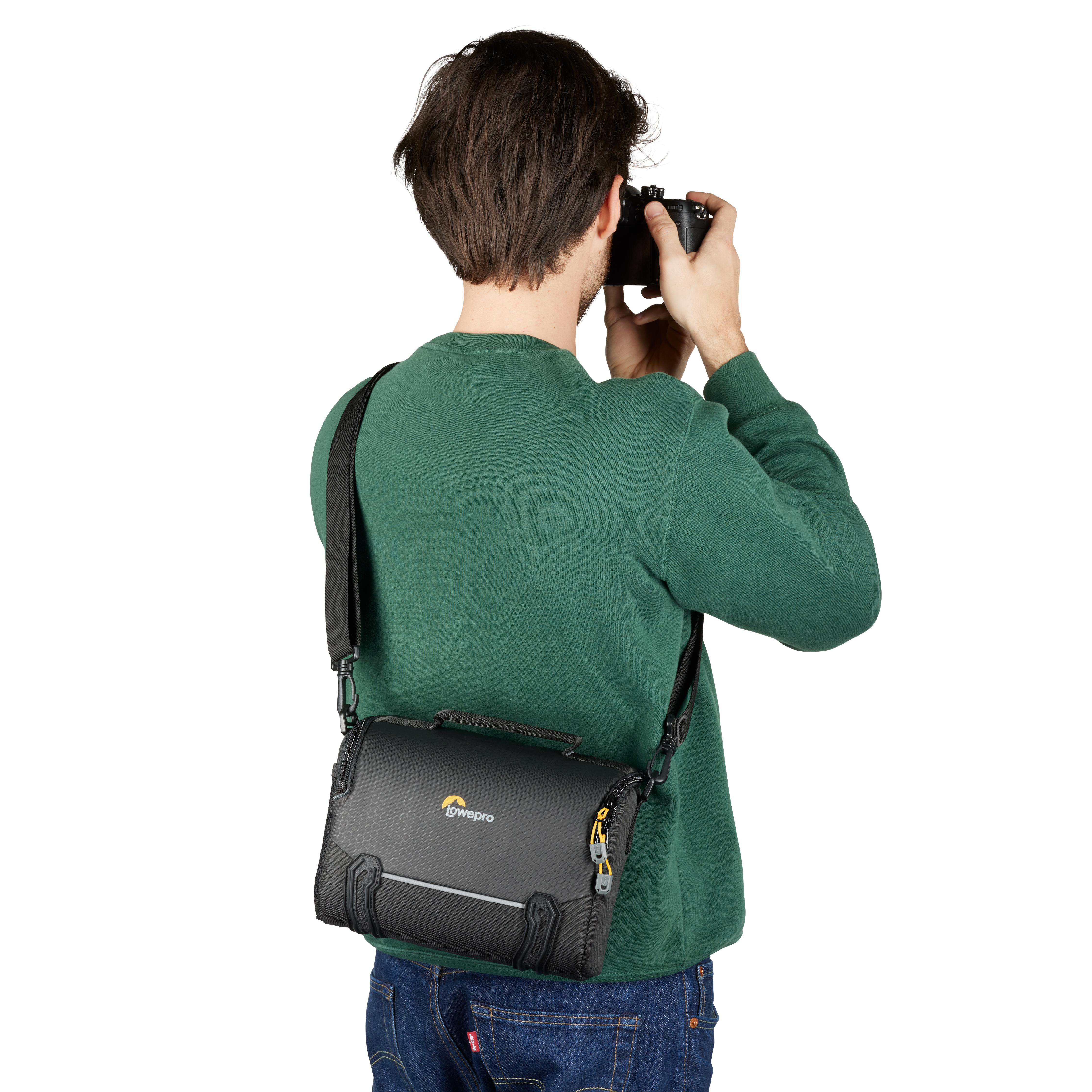 Ein Mann, von hinten gesehen, hält eine Kamera und trägt eine Lowepro-Kameratasche.
