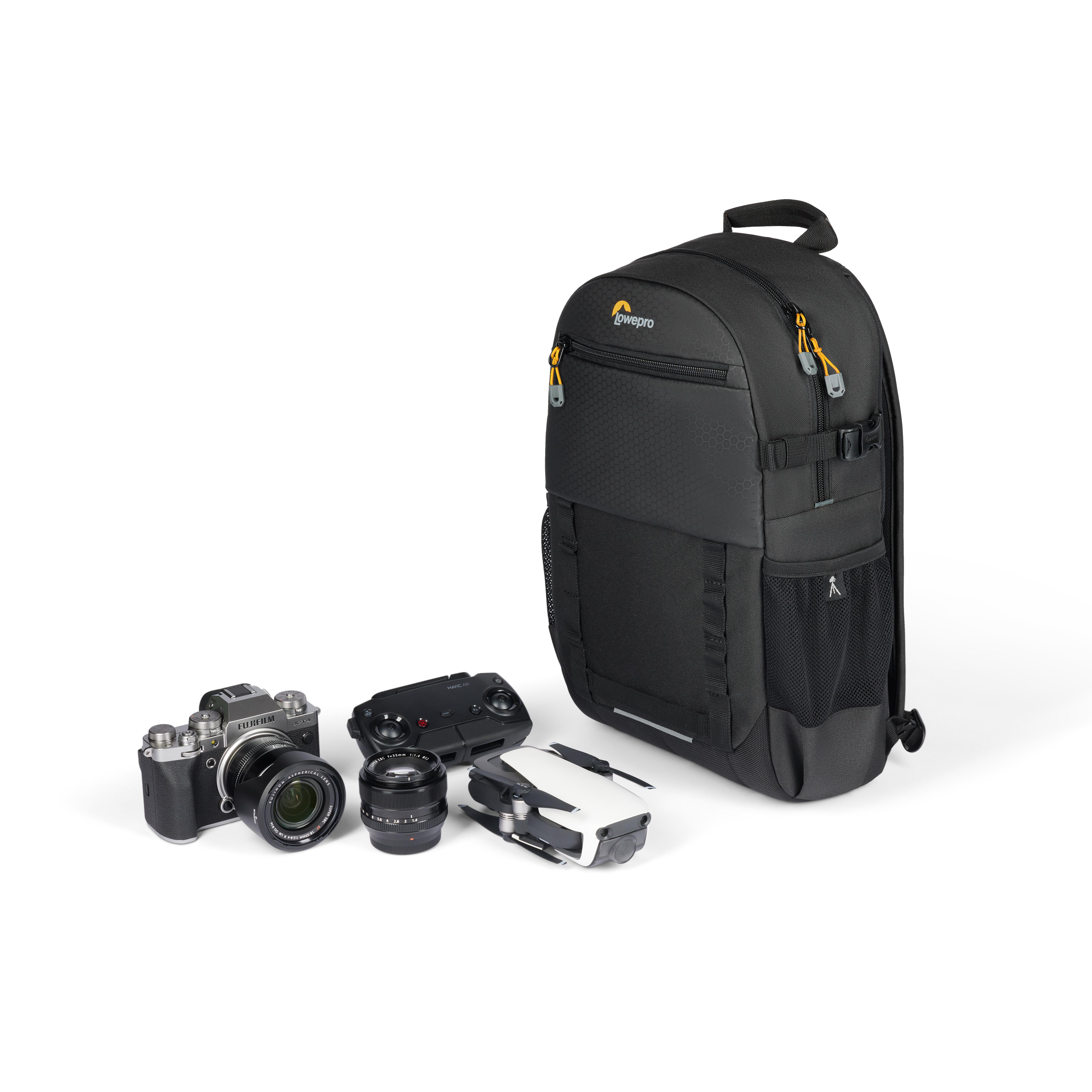 Schwarzer Lowepro Kamera-Rucksack mit Kameras, Objektiven, einer Drohne und einer Fernbedienung auf weißem Hintergrund.
