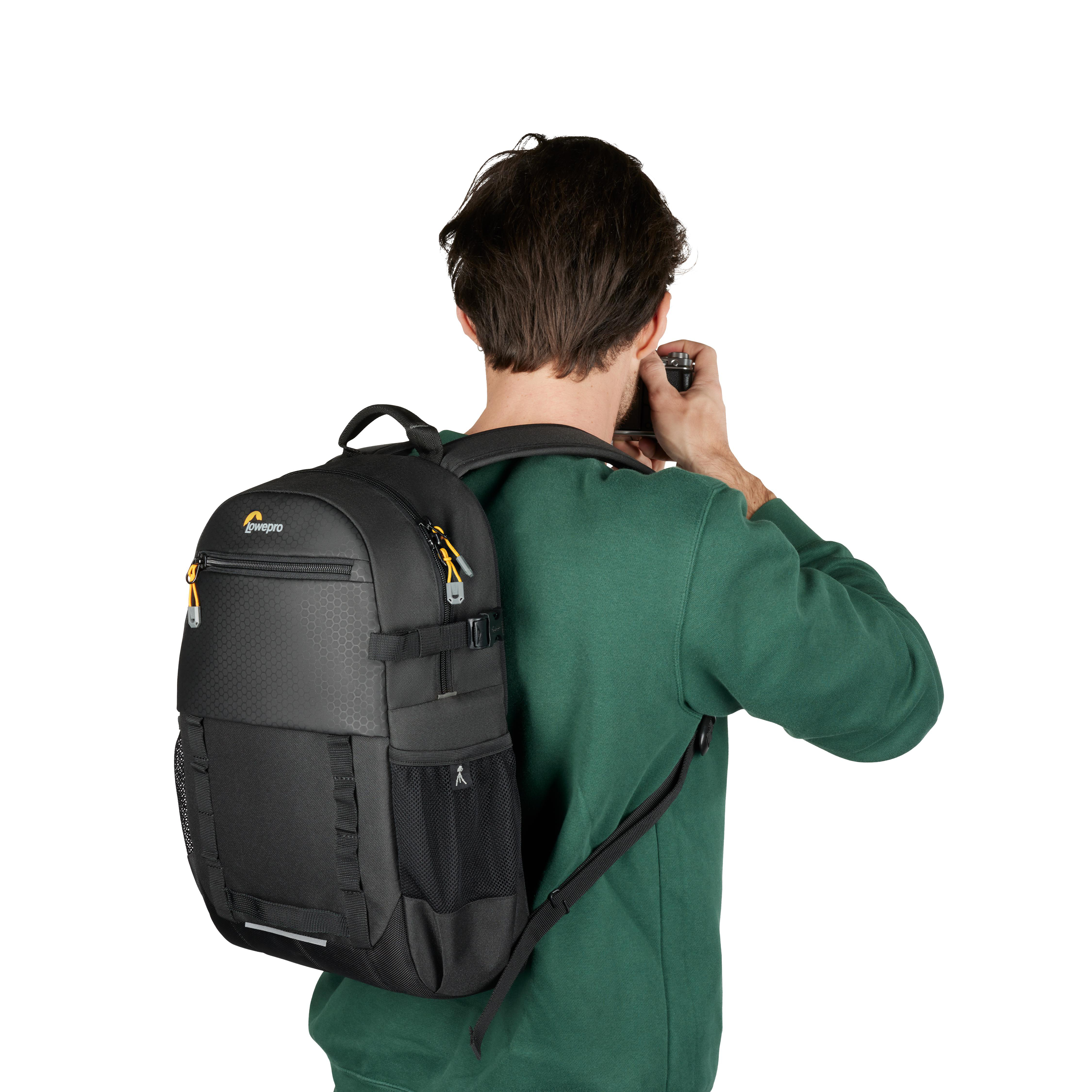 Mann mit Rucksack benutzt Kamera, weißer Hintergrund.