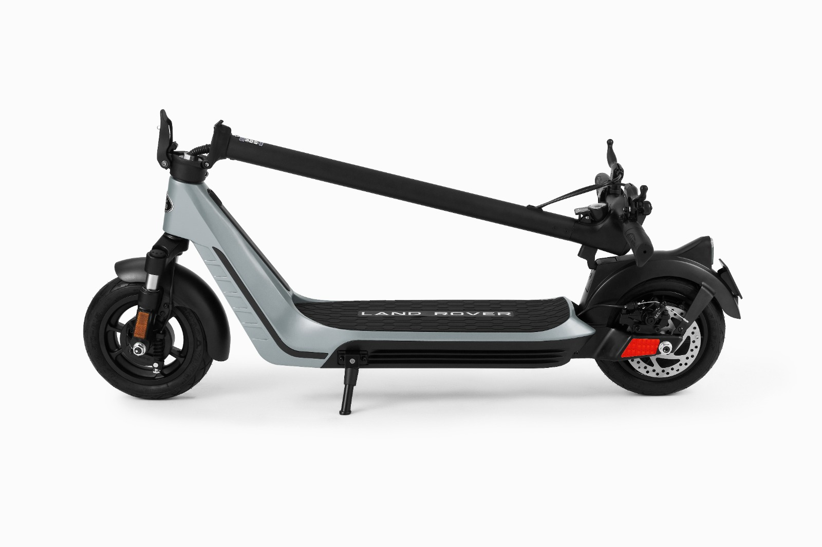 Gri bir Land Rover elektrikli scooter, katlanmış, siyah bir gidon ve beyaz bir zemin.