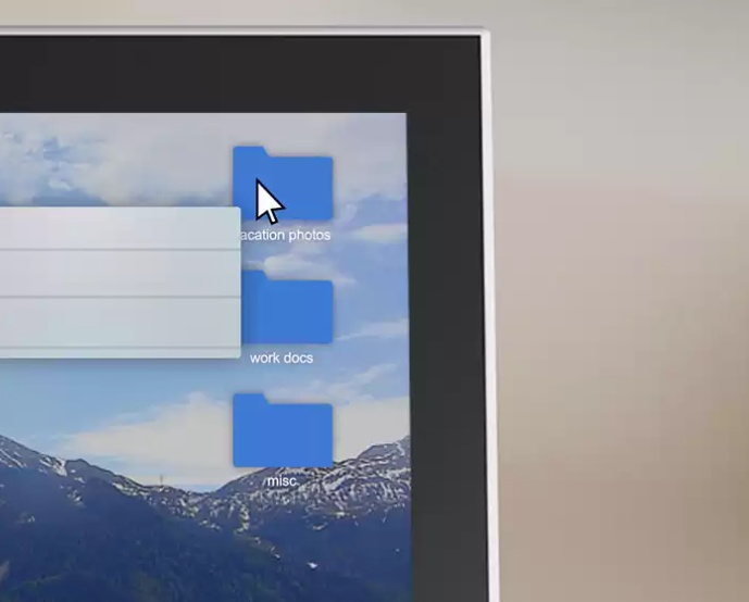 Schermo del computer che mostra tre icone di cartelle blu etichettate foto vacanze, documenti di lavoro e altro.