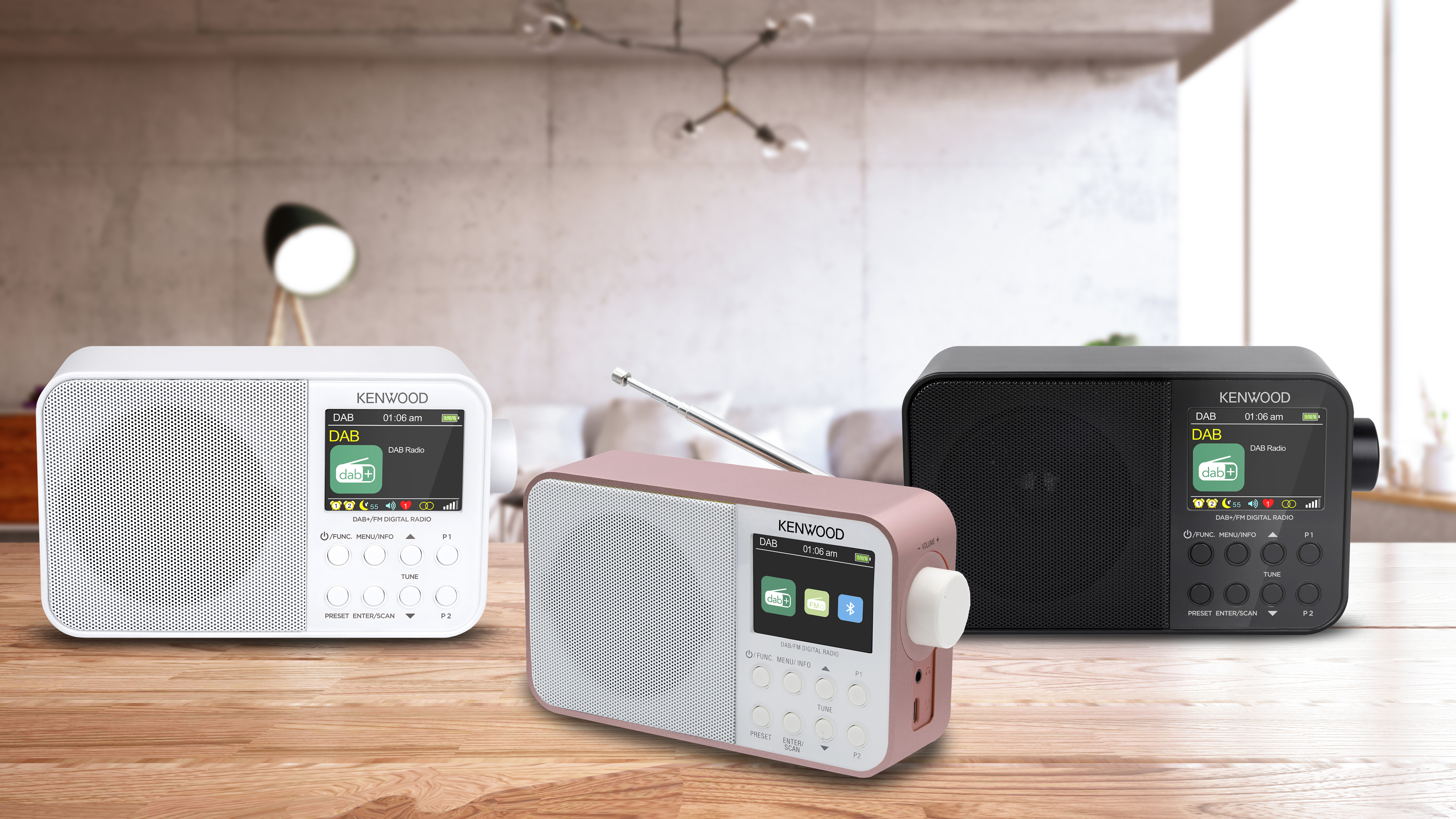 Drei digitale Kenwood-Radios auf einem Holztisch. Eines weiß, rosa und schwarz, mit Bildschirmen.